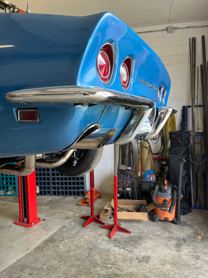 Blue 1969 Corvette on a lift in a garage with tools and equipment around