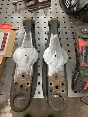 Two metal brackets on a pegboard with tools in the background