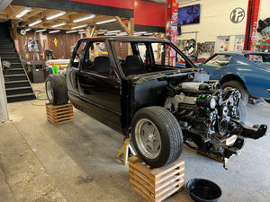 Car chassis with engine exposed in a workshop setting