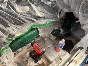 Construction site with tools and materials on a concrete floor, covered by plastic sheeting.