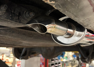 Close-up of a car exhaust system with a visible brand logo in a workshop setting.