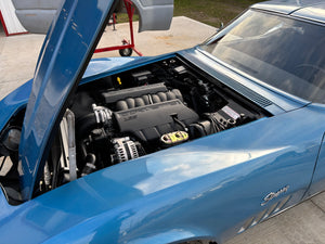 Blue 1969 Corvette with open hood revealing LS3 engine, parked outdoors.