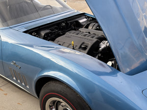 Blue 1969 Corvette with open hood revealing engine compartment on a concrete surface
