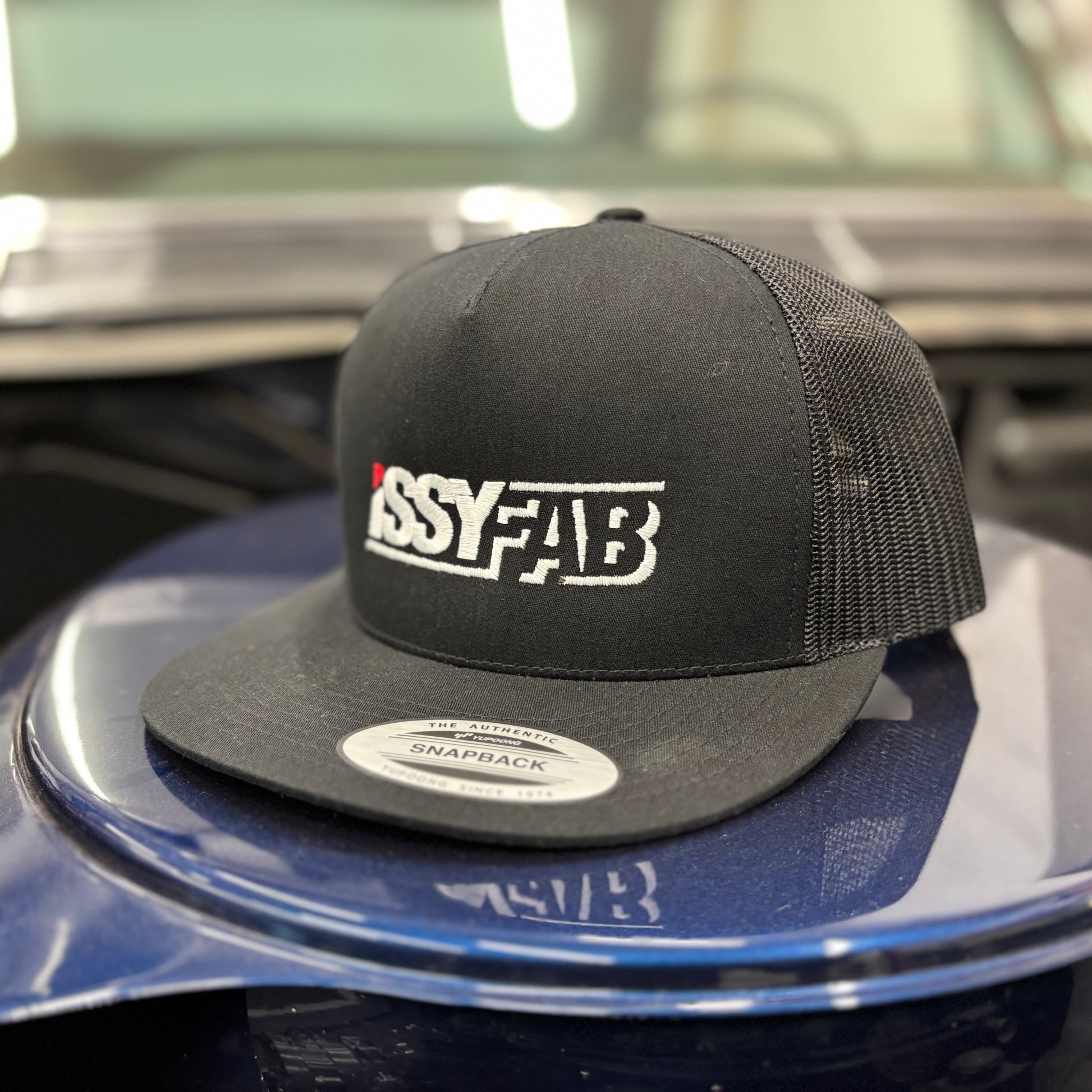 Black cap with 'ISSYFAB' logo on a car hood
