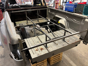 Open truck bed with metal frame and tools in a workshop setting