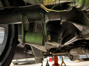 Close-up of a car's suspension system with a green shock absorber.