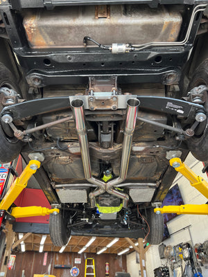 Undercarriage of a vehicle with suspension components and yellow lift stands.