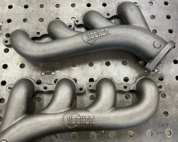 Two HOOKER exhaust manifolds on a perforated metal surface