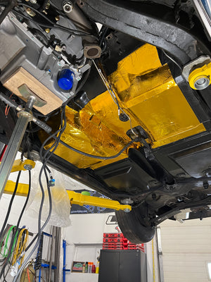 Undercarriage of a vehicle with yellow protective cover in a garage setting