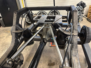 Mechanical vehicle frame with wheels and suspension components in a workshop setting