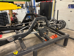 Metal frame with wheels on a workbench in a workshop setting