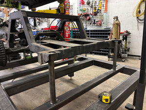Metal frame structure in a workshop with tools and equipment in the background
